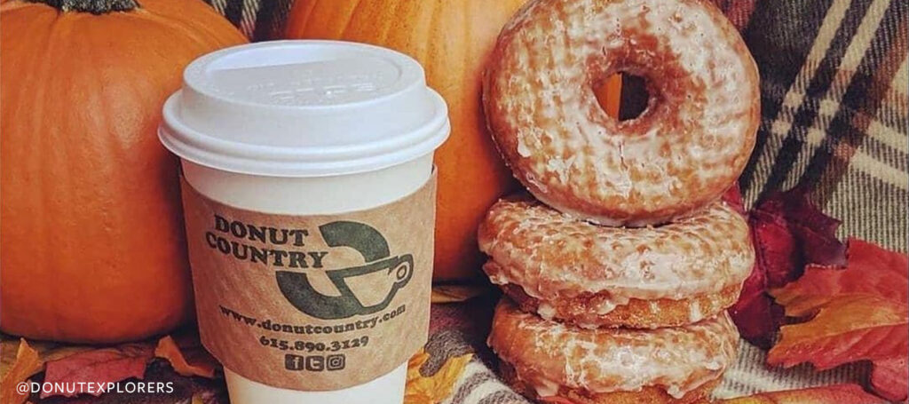 A coffee and stack of donuts from Donut Country in front of pumpkins