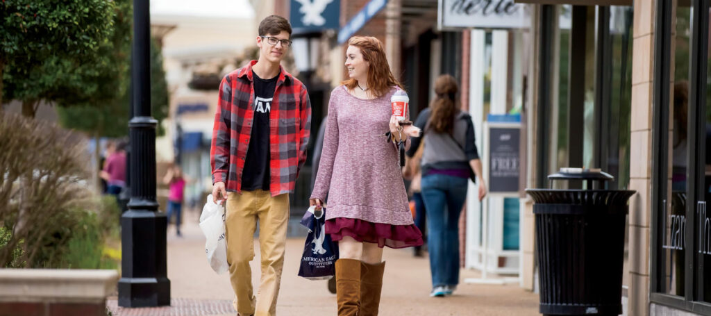 Couple walking down sidewalk with shopping bags