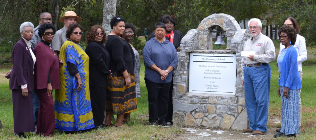 Group standing at a monument for The Cemetery School