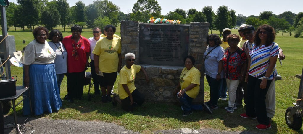 Group posing around the trail marker at Evergreen Cemetery